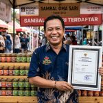 Seorang pelaku UMKM tersenyum puas sambil memegang sertifikat legalitas merek dagang di depan produk jualannya